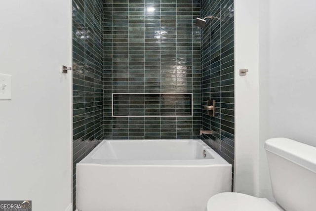 bathroom with toilet and tiled shower / bath