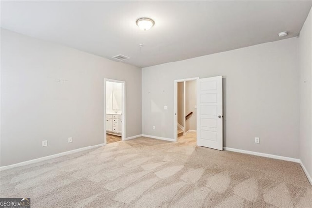 unfurnished bedroom with light colored carpet and ensuite bathroom