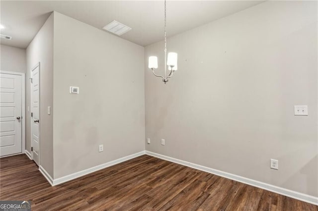 unfurnished dining area featuring an inviting chandelier and dark hardwood / wood-style flooring