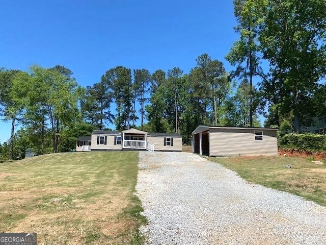 manufactured / mobile home featuring an outbuilding, driveway, covered porch, and a front lawn