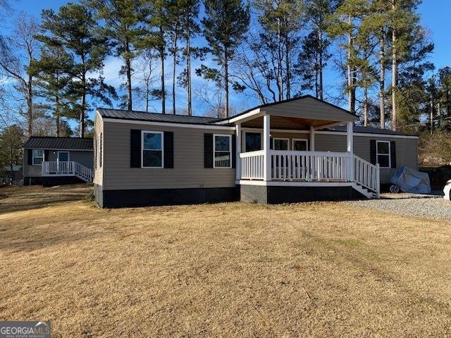 manufactured / mobile home with a front yard, a porch, and metal roof