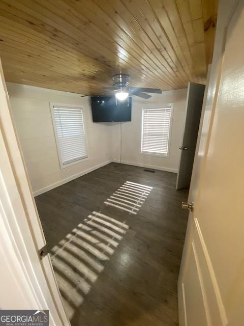 basement with baseboards, a ceiling fan, dark wood-style floors, and wood ceiling