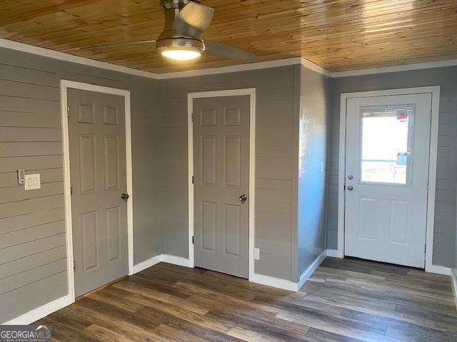 foyer entrance featuring crown molding, ceiling fan, dark wood finished floors, wood ceiling, and baseboards