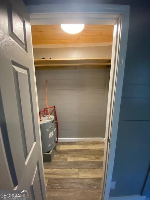 spacious closet featuring water heater and hardwood / wood-style floors