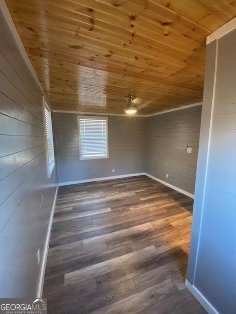 empty room with wood ceiling, wood finished floors, wooden walls, and baseboards
