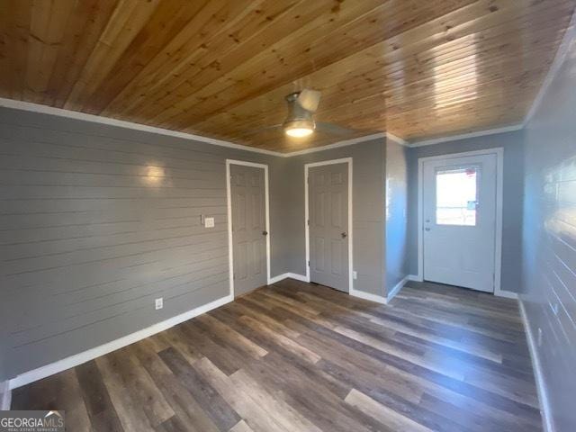 unfurnished dining area featuring baseboards, ornamental molding, a ceiling fan, wooden ceiling, and wood finished floors