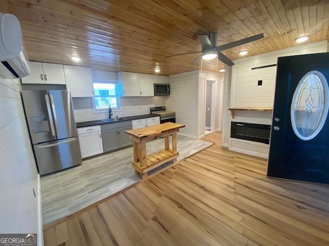 kitchen with light wood-style floors, ceiling fan, wood ceiling, and appliances with stainless steel finishes