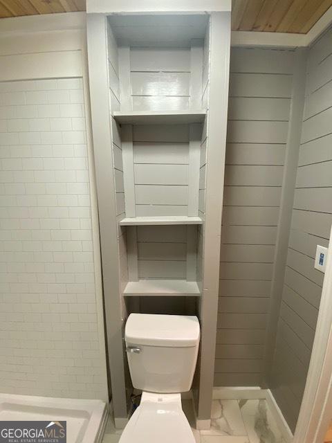 bathroom with wood walls and toilet