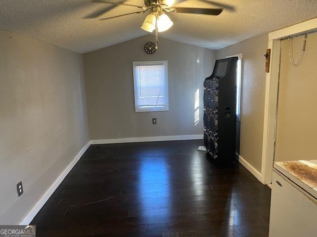 empty room featuring a textured ceiling, wood finished floors, ceiling fan, and vaulted ceiling
