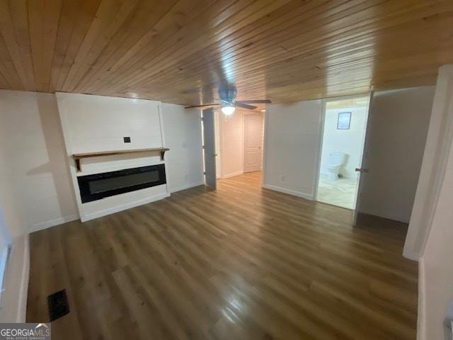 unfurnished living room with a ceiling fan, a glass covered fireplace, wooden ceiling, wood finished floors, and baseboards