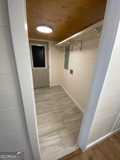 corridor with light wood-type flooring, electric panel, and wooden ceiling