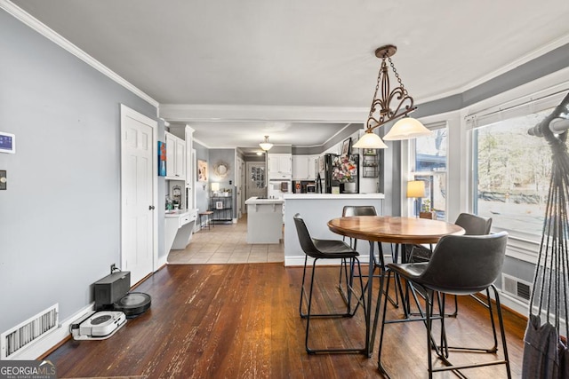 dining room featuring ornamental molding and light wood-type flooring