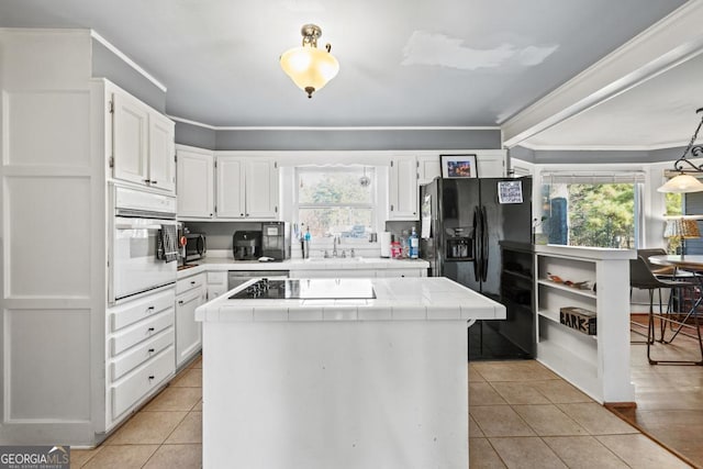 kitchen with black appliances, tile counters, light tile patterned floors, and white cabinets