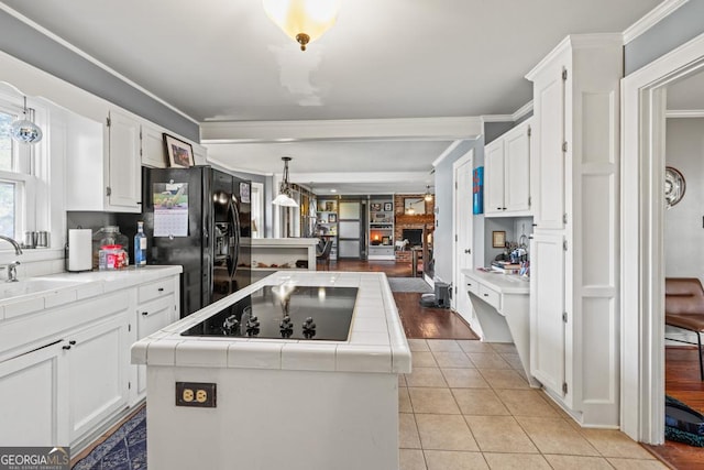 kitchen with white cabinetry, a kitchen island, tile counters, and black appliances