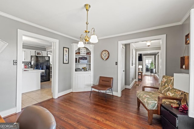 living area with ornamental molding, hardwood / wood-style floors, and a notable chandelier