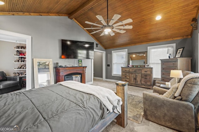 carpeted bedroom featuring ceiling fan, vaulted ceiling with beams, wooden ceiling, and a fireplace