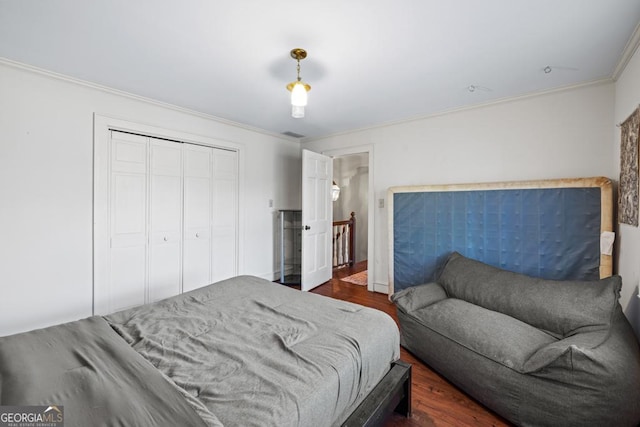 bedroom featuring dark wood-type flooring, ornamental molding, and a closet