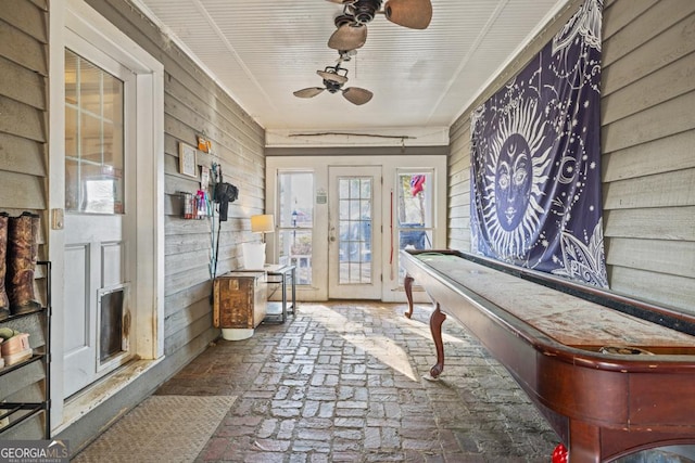 interior space featuring wooden walls and ceiling fan