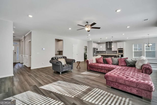 living room featuring ceiling fan with notable chandelier and dark wood-type flooring