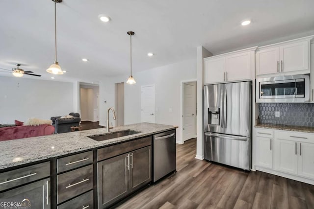 kitchen with appliances with stainless steel finishes, white cabinetry, hanging light fixtures, and sink