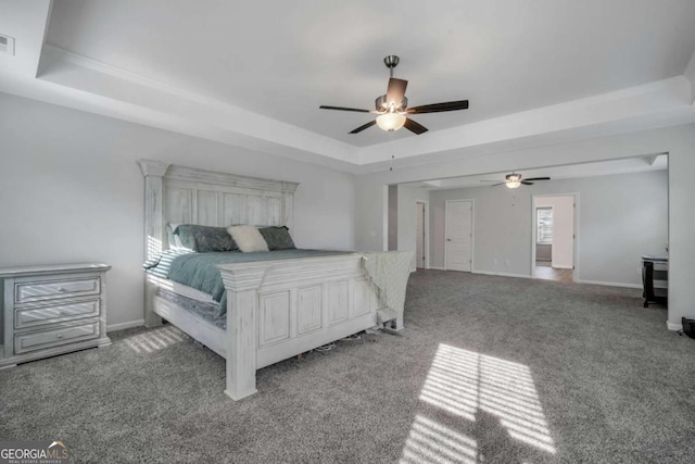 bedroom with a raised ceiling, ceiling fan, and carpet floors