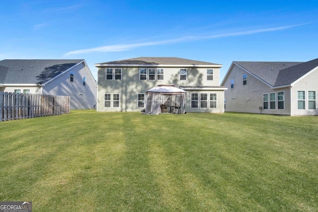 rear view of house with a lawn and a gazebo