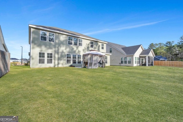 rear view of property featuring a lawn and a gazebo