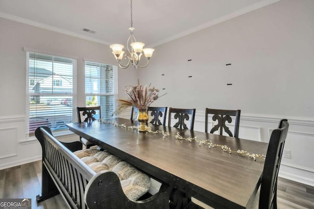 dining space with crown molding, dark wood-type flooring, and an inviting chandelier