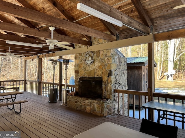 wooden terrace with ceiling fan and a stone fireplace