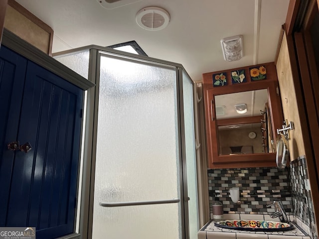 bathroom with a shower with shower door and decorative backsplash