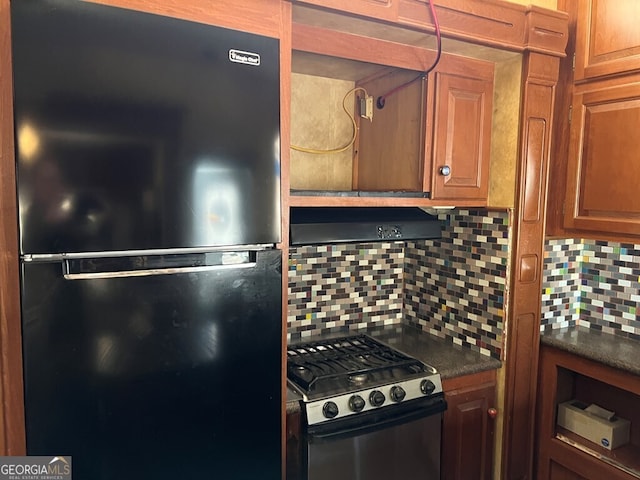 kitchen featuring backsplash, gas range oven, and black fridge