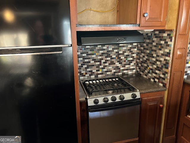 kitchen with black refrigerator, decorative backsplash, and gas range