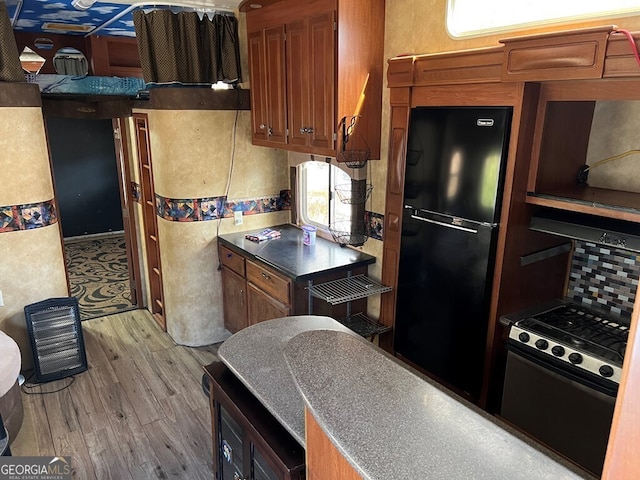 kitchen with black fridge, stove, and light wood-type flooring