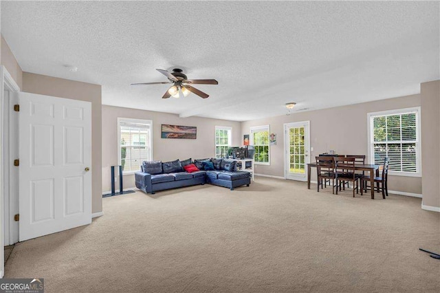 living room featuring ceiling fan, light carpet, and a textured ceiling