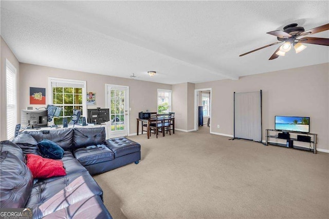 carpeted living room featuring a textured ceiling, ceiling fan, and beamed ceiling