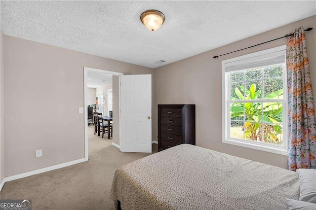 bedroom with a textured ceiling and light colored carpet