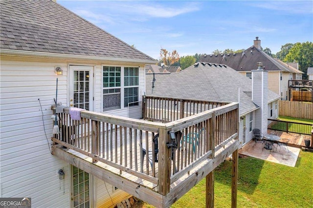 wooden terrace featuring a lawn and a patio area