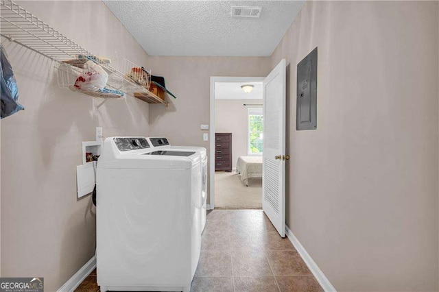 clothes washing area featuring separate washer and dryer, a textured ceiling, and electric panel