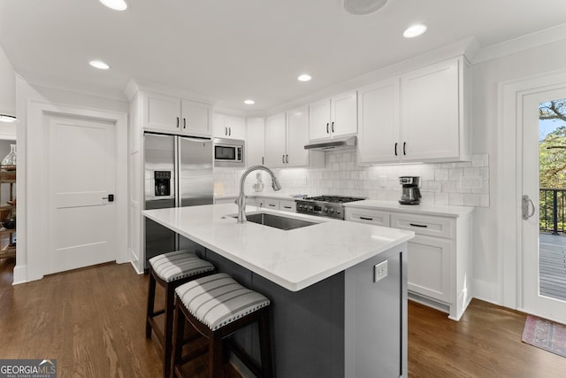 kitchen featuring a center island with sink, appliances with stainless steel finishes, dark hardwood / wood-style floors, white cabinets, and sink