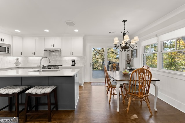 kitchen featuring stainless steel microwave, a healthy amount of sunlight, white cabinets, and a notable chandelier