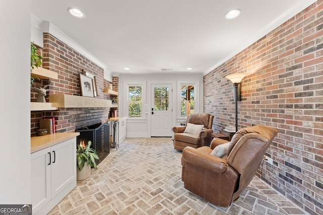 living room with brick wall, ornamental molding, and a fireplace