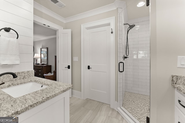 bathroom featuring a shower with shower door, vanity, and crown molding