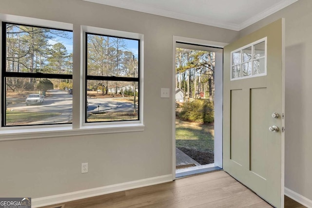 entryway with ornamental molding and light hardwood / wood-style flooring