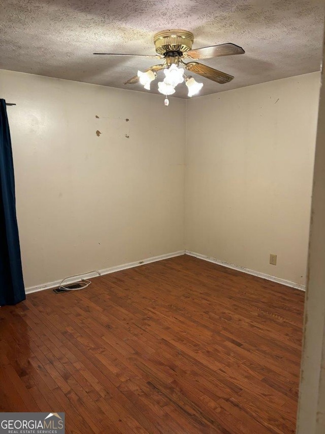 spare room with a textured ceiling, dark wood-type flooring, and ceiling fan