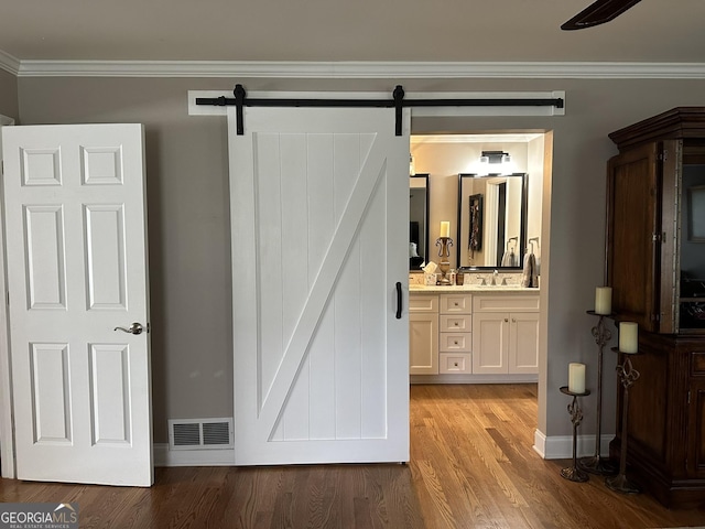 bathroom featuring wood-type flooring, crown molding, and vanity