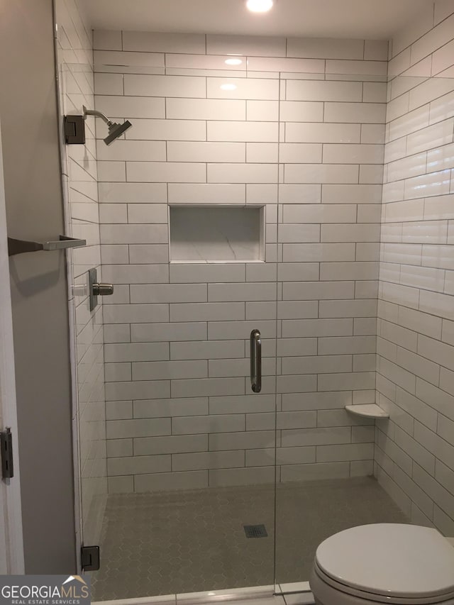 bathroom with toilet and a shower with shower door