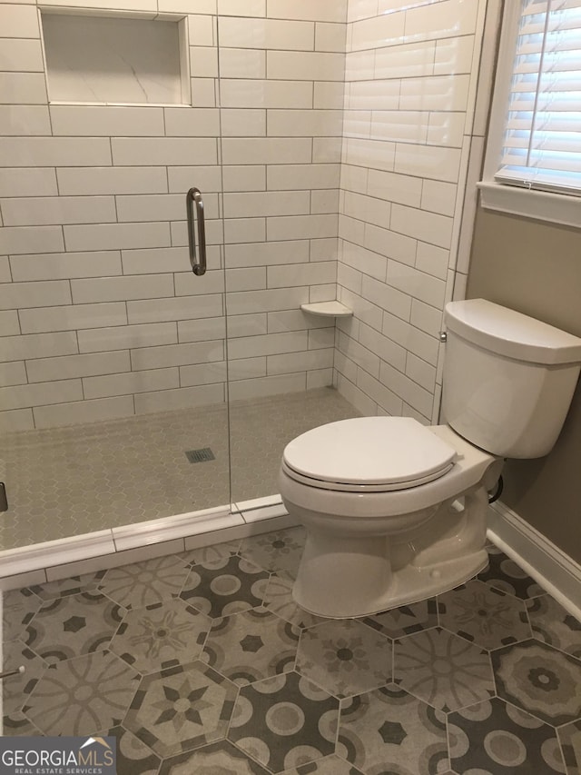 bathroom with tile patterned floors, an enclosed shower, and toilet