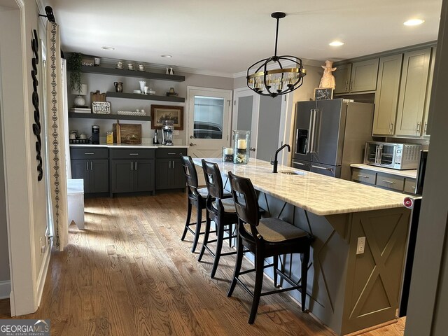 kitchen featuring crown molding, a center island with sink, high end refrigerator, and gray cabinets