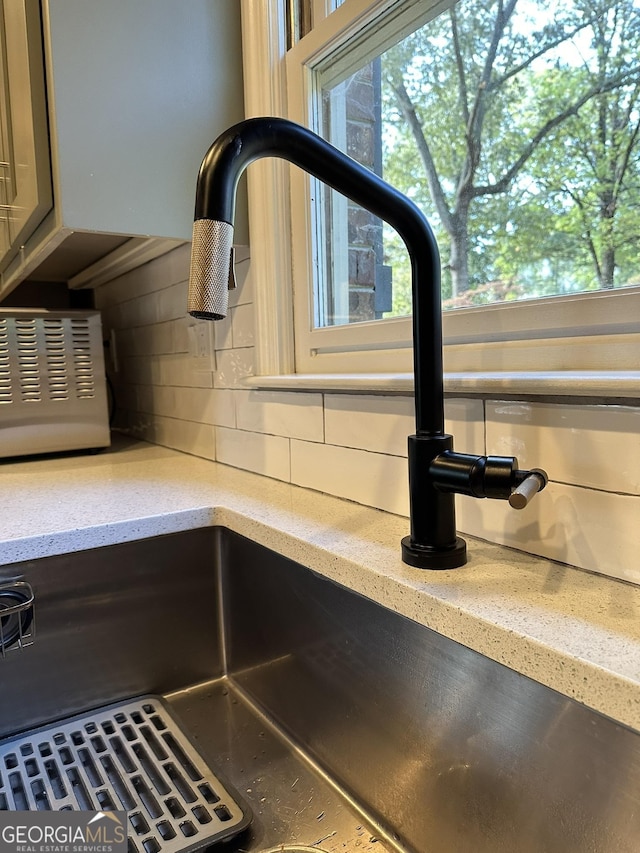 room details featuring sink, light stone countertops, and decorative backsplash