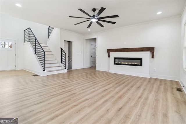 unfurnished living room featuring ceiling fan, light wood-type flooring, and ornamental molding